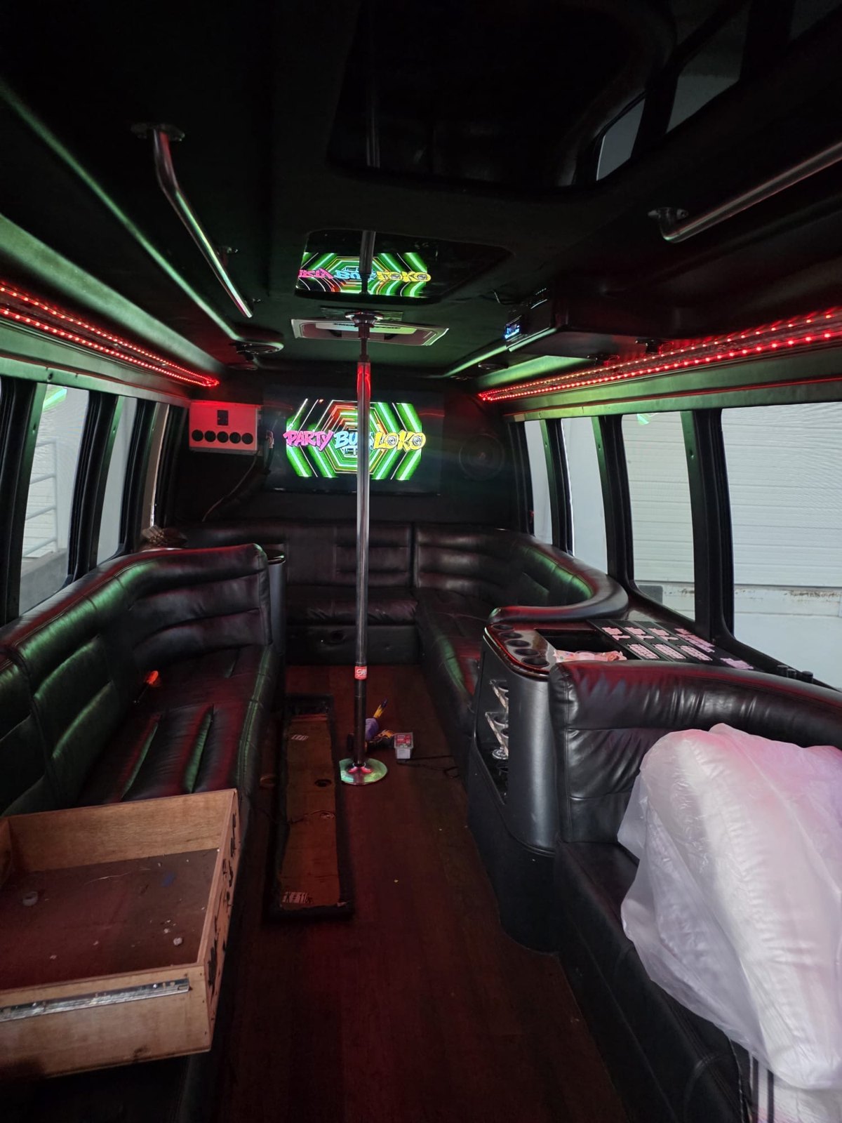 Red LED lighting, seating and central dance pole inside Party Loko Bus